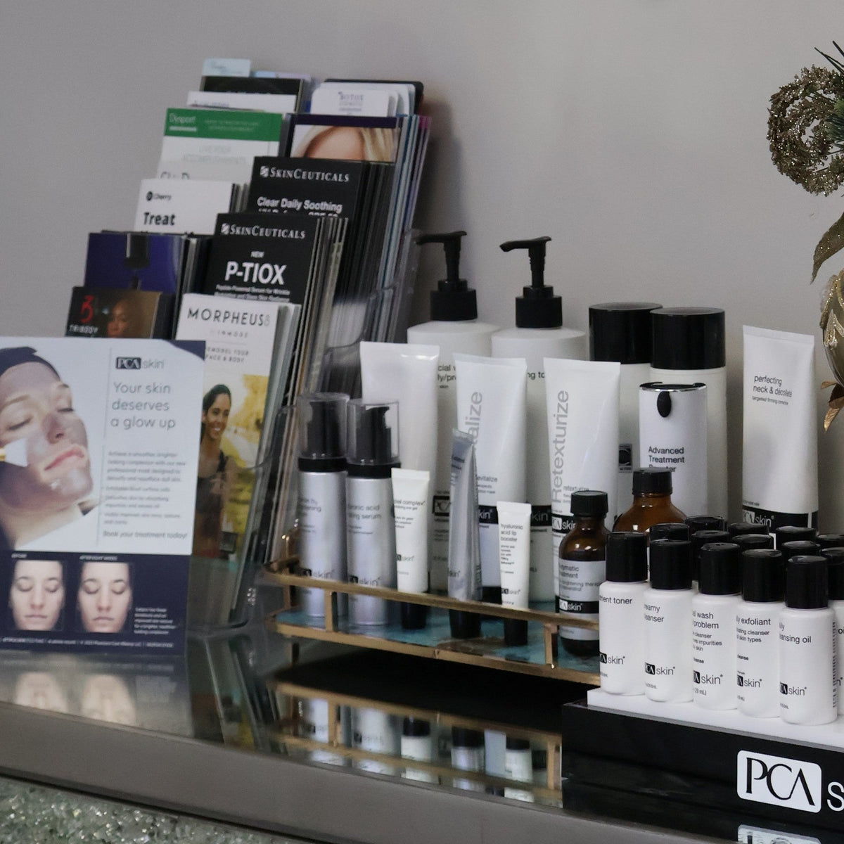 Lineup of PCA Skin medical-grade serums, moisturizers, and sunscreen arranged on a wood credenza inside RX MD Solutions medspa in Plano.